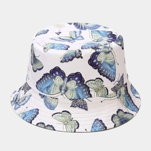 Detailed view of white canvas bucket hat featuring blue butterfly patterns and reinforced stitching
