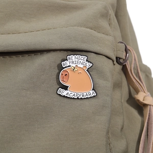 Detailed close-up of cute Capybara enamel pin on olive green canvas bag strap