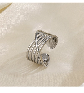 Macro view of polished silver multi-layer crossover open ring on champagne silk fabric