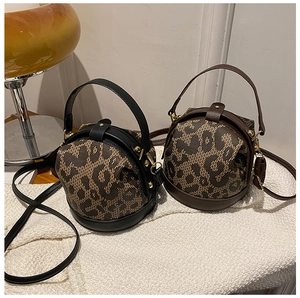 Detail of leopard print cylinder bags in black and brown faux leather with shoulder straps