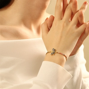 Elegant gold bracelet with dragonfly pendant and colorful gemstones on a woman's wrist