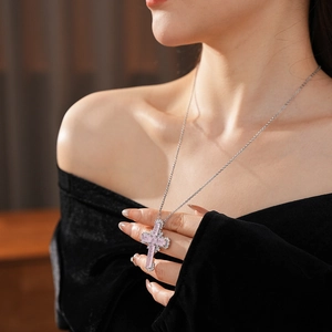 Detail of cross pendant necklace featuring pink zircon stones and pavé crystals on a silver chain