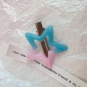 Detaillierte Makroansicht einer blau-rosa Stern-Haarklammer aus Harz auf weißem Papier