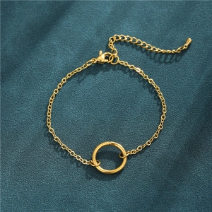 Detailed macro view of gold chain bracelet with geometric round charm on fabric