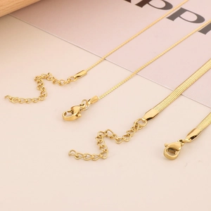 Detailed shot of golden lobster clasp and flat snake chain extension for jewelry