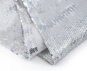 Detailed macro view of sparkling silver sequin fabric with metallic coating on mesh base