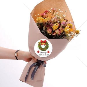 Close-up of Merry Christmas wreath stickers on floral packaging with a white background