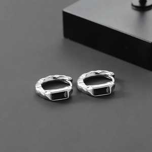 Detailed view of silver hoop earrings with hammered texture and rectangular black stones