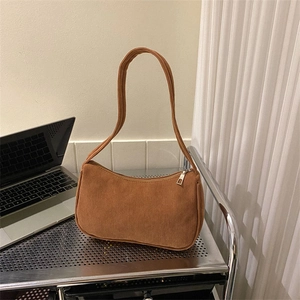 Brown corduroy crescent shoulder bag with zipper closure on a minimalist metal shelf