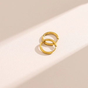 Macro detail of high-polished 18K gold-plated stainless steel hoop earrings with shadows