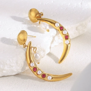 Macro detail of 18K gold crescent earrings with white pearls and pink gemstones