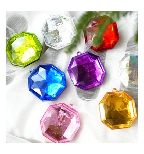 Flat lay of colorful diamond-shaped acrylic ornaments on white fabric with pine needles