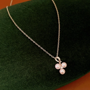 Macro detail of pink pearls and tiny diamond on a silver chain over green velvet