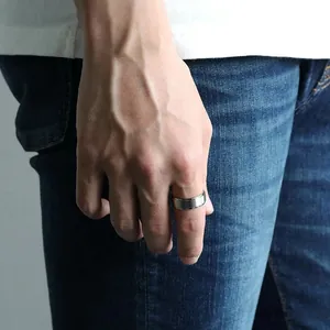 Close-up of a silver brushed matte wedding band for men shown on finger