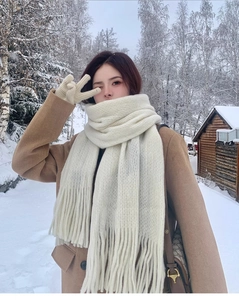 Detail of creamy white chunky knit scarf and matching fringe gloves in a snowy winter setting
