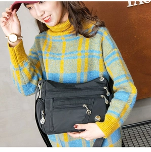 Detail of multi-pocket black nylon crossbody bag with metallic logo for middle-aged women