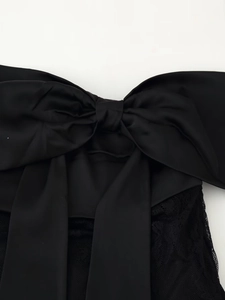 Gros plan sur un grand nœud en satin noir et les détails de dentelle de la mini-jupe