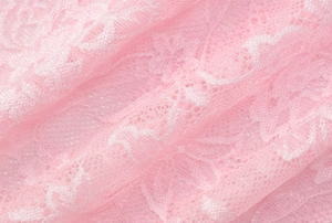 Primer plano de tela de encaje rosa que muestra bordados florales y una textura suave