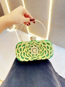 Detail of luxury green sequin evening clutch bag with golden rhinestone flower and ring handle
