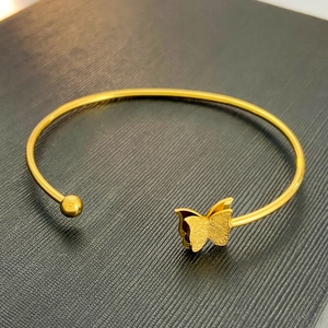 Elegant gold open butterfly bangle with frosted finish on a black jewelry box