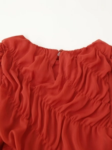 Detailed close-up of red ruched chiffon dress collar with a small matching button