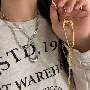 Detail of gold and silver cuban link chain with oversized safety pin pendant necklace