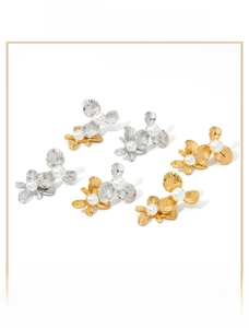 Detail of floral earrings in silver and gold tones with textured petals and center pearls