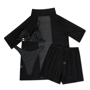 Flat lay of a black four-piece beachwear set featuring a mesh shirt and bikini