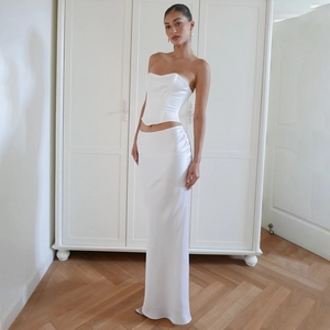 Dettaglio di un set in raso bianco con crop top e gonna lunga indossato da una modella