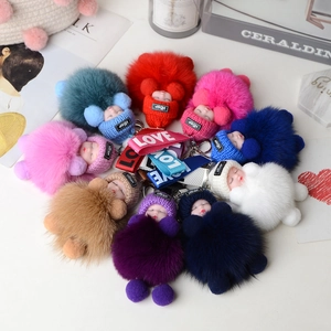 Macro shot of colorful sleeping doll fox fur pom-poms with LOVE ribbon and metal keychains