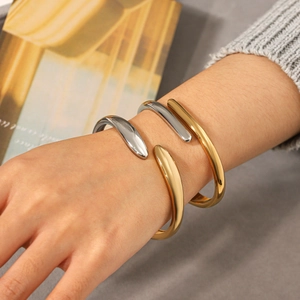 Close-up of minimalist open cuff bracelet in gold and silver finish worn on wrist
