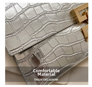 Close-up of silver crocodile embossed leather clutch with golden H-shaped buckle