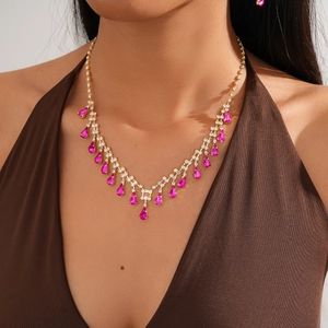 Detail of luxury gold necklace featuring fringe tassel and pink teardrop pendant