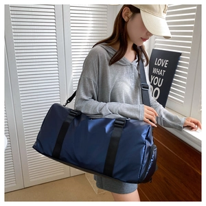Deep blue fitness travel bag with black straps worn by model against a white background