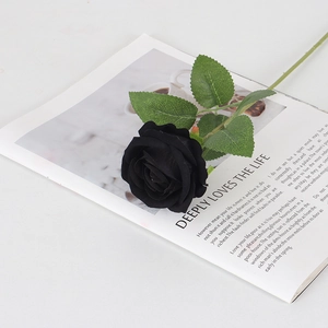 Rosa artificial de terciopelo negro con hojas verdes en revista para decoración