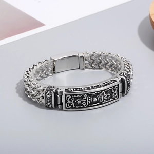 Detail of vintage totem relief and braided steel chain on a men's punk bracelet