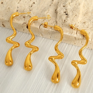 Polished gold wavy drop earrings with minimalist abstract curves on travertine stone