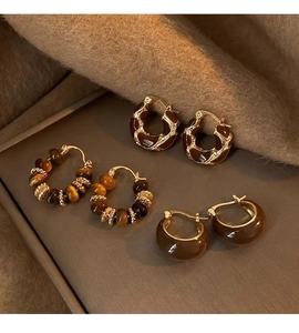 Detailed view of three pairs of vintage tiger eye and brown resin geometric hoop earrings