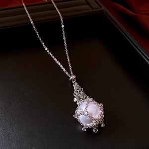Detail of a large white pearl pendant with silver diamond-set hollow mesh and fine chain