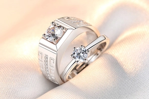 Close-up of couple rings featuring six-prong zircon setting and engraved geometric texture