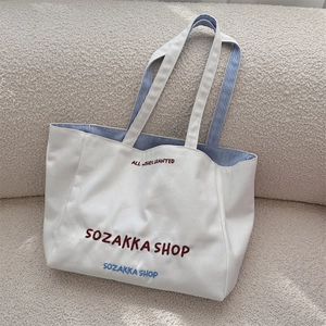 Makroaufnahme der Canvas-Tasche mit roter Stickerei und gestreiftem Innenfutter