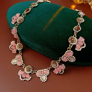 Detail of vintage flower necklace with pink crystal and tiger eye stone drops on velvet