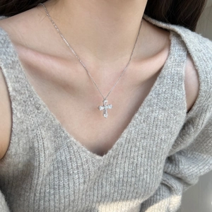 Detail shot of a S925 sterling silver cross pendant with sparkling zircon on a model
