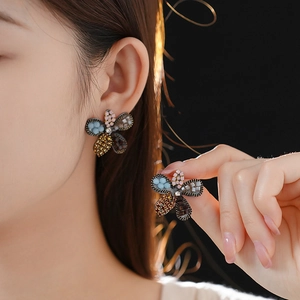 Detail of flower-shaped stud earrings with colorful crystal beads on a model