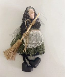 Detailed close-up of a handcrafted witch doll with a green dress and miniature broom