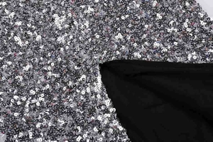 Détail de paillettes argentées cousues sur résille noire pour une robe scintillante