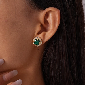 Close-up of elegant flower-shaped emerald green earrings with zircon halo on model