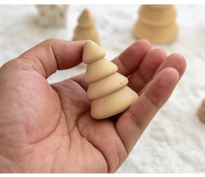 Miniature wooden Christmas tree ornament held in hand showing natural wood grain texture