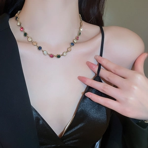 Close-up of luxury gold chain bracelet with colorful gemstones worn on a female wrist