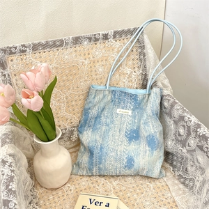 Close-up of light blue tie-dye tote bag with ethnic patterns and white woven label